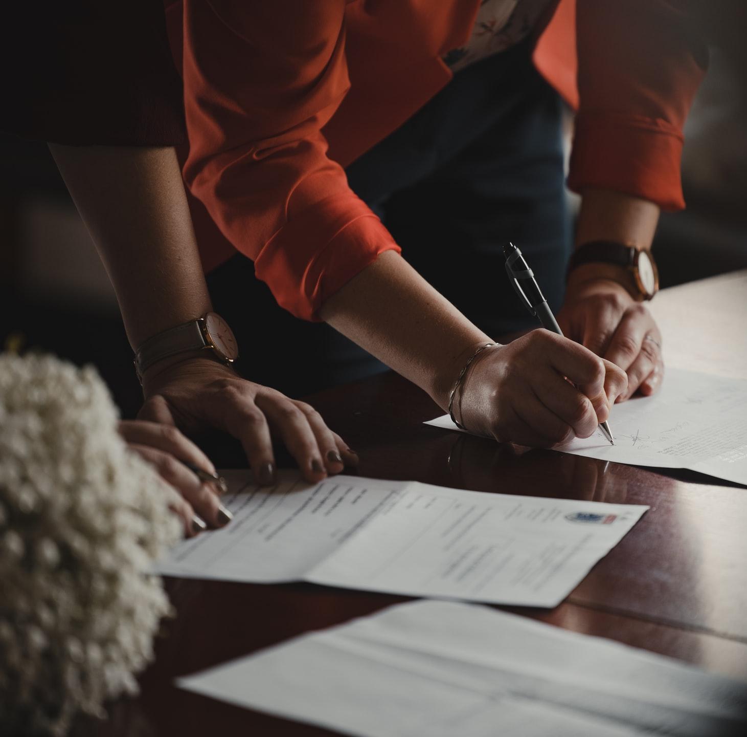 person in orange long sleeve shirt writing on white paper
